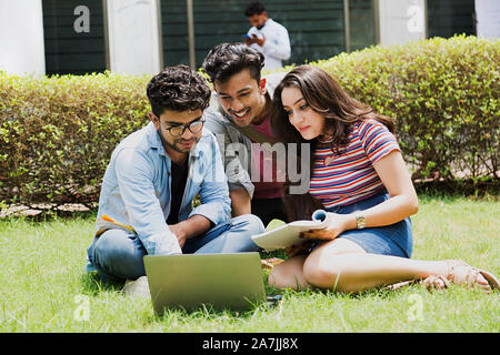 Three College Boys And Girl Students Friends Studying Book With Laptop in-Outside Campus Stock Photo
