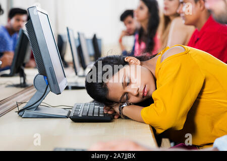 Tired Young Woman College Student Sleeping On The Table With Computer In Classroom Stock Photo