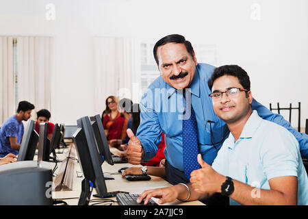 College Professor With Young-man Student Studying Computer And Showing Thumbs-up in Computer lab Stock Photo