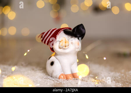 Decorative Christmas-themed figurines. Cute pig in a hat. Christmas tree decoration. Festive decor, warm bokeh lights Stock Photo