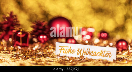 panorama with shiny gold and red christmas decoration and german text which means merry christmas Stock Photo
