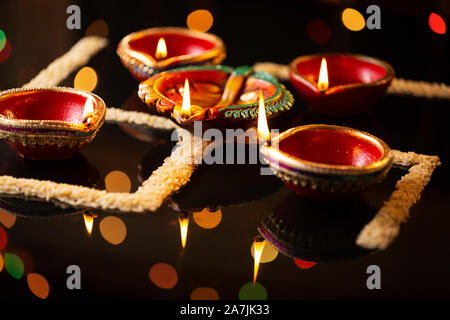 Burning diyas oil-lamps Lighting With Rice arranged to form swastik symbol on Diwali Festival Stock Photo
