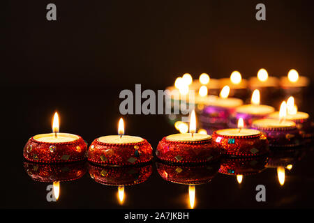 curved line of lit tea lights in the dark background on Diwali Festival Stock Photo