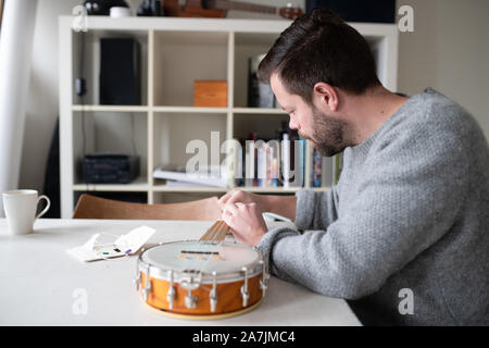 man replacing strings on banjo ukulele Stock Photo