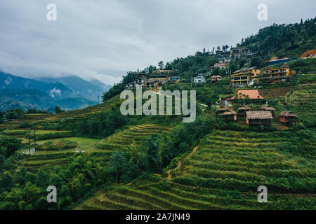 Top aerial birdseye view of harvested green rice terraces and small shacks in Sapa, North Vietnam. Shot in Autumn, October 2019 Stock Photo