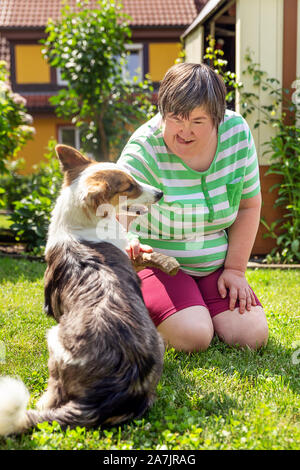 mentally disabled woman with a second woman and a companion dog, concept learning by animal assisted living Stock Photo