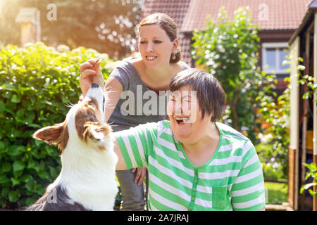 mentally disabled woman with a second woman and a companion dog, concept learning by animal assisted living Stock Photo