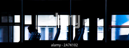 One blurry person sitting alone inside the empty bus driving in the night, the last passenger, through windows from the outside Stock Photo