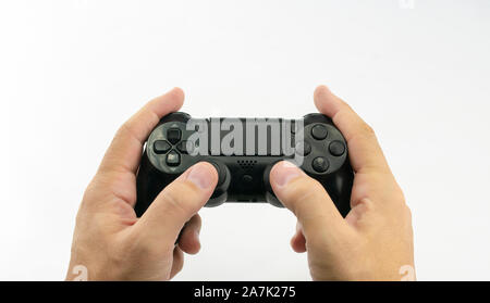 Video game console in black, with joysticks and buttons in the hands of a caucasian man on white background Stock Photo