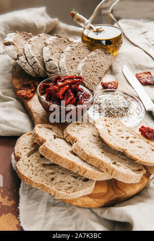 Healthy rye wholegrain bread with olives, avocado and sun-dried tomatoes on a wooden farmer's table. Homemade cake. traditional Italian food. Stock Photo