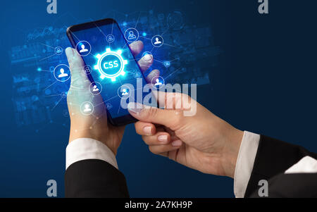 Female hand holding smartphone with CSS abbreviation, modern technology ...