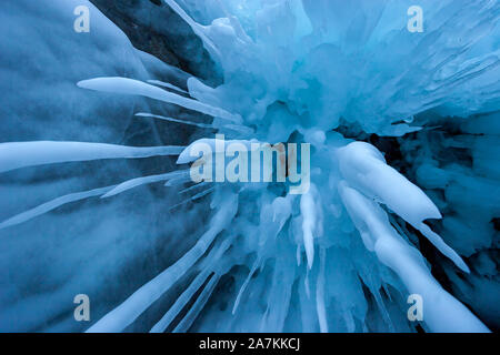 Long melted icicles shot from below. Sharp icicles of blue color. A lot of ice around. Winter frozen background. Stock Photo