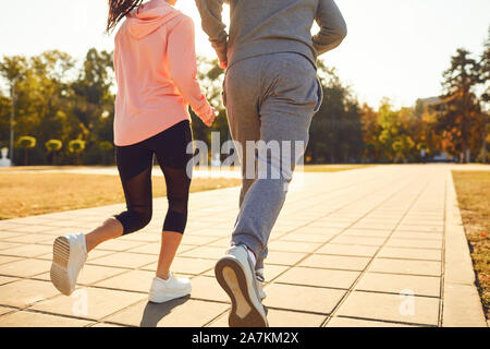 Back view sporty couple are running along the city street in the morning. Stock Photo