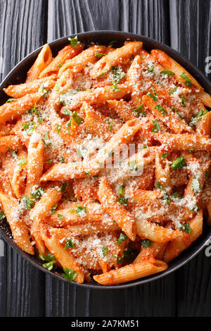 Penne alla vodka is a pasta dish made with vodka, usually made with heavy cream, crushed tomatoes, onions close-up in a plate on the table. Vertical t Stock Photo