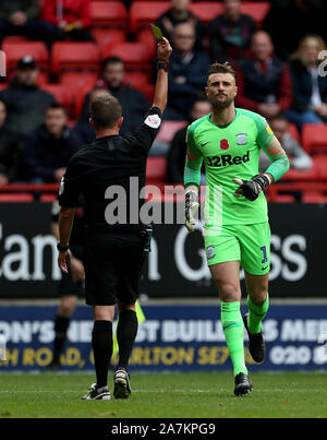 Preston North End goalkeeper Declan Rudd is shown a yellow card by referee David Webb during the Sky Bet Championship match at The Valley, Charlton. Stock Photo