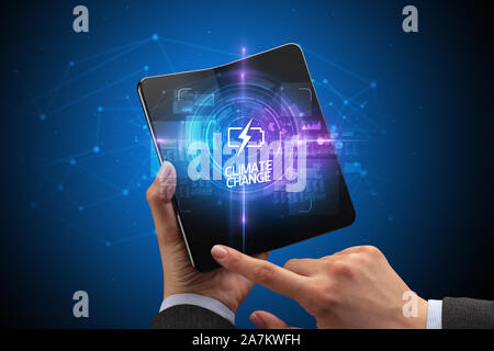 Businessman holding a foldable smartphone with WEB TRAFFIC inscription, new technology concept CLIMATE CHANGE Stock Photo