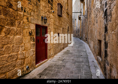 Ancient city of Mdina in Malta, shady, narrow street and medieval stone walls houses in the old capital. Stock Photo
