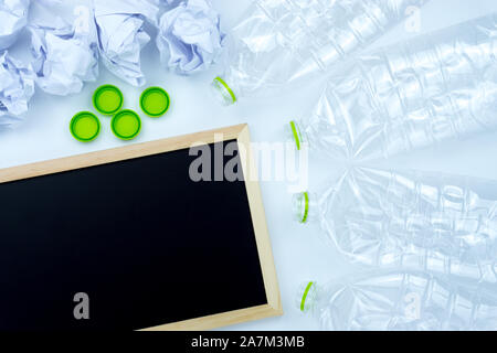 Recycling. The frame of used plastic bottle, blackboard and crumpled paper on white background with copy space. Recycle and reuse concept