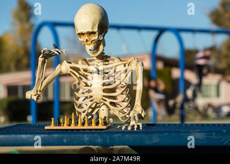 Skeleton makes a move with his king on the chess board Stock Photo