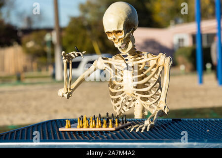 Skeleton makes a move with his king on the chess board Stock Photo