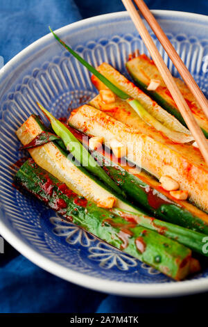 Korean Kimchi pickle cucumber.Marinated cucumbers with chili pepper,garlic,greens onion in blue plate close-up.Healthy vegan snack with probiotic Stock Photo