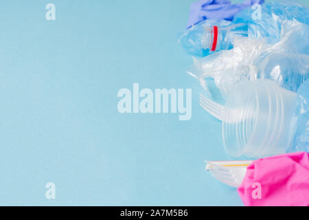 Top view of various kinds of disposable plastic waste on blue background, copy space. Stock Photo