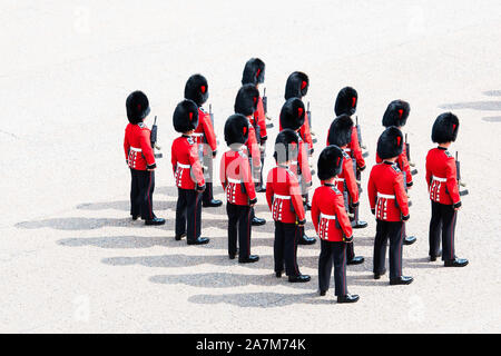 British Army soldiers of the Coldstream Guards stand in perfect formation on parade in their iconic scarlet tunics and bearskin caps Stock Photo