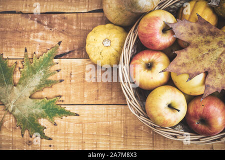 Fresh organic apples and pumpkins in a basket on a wooden table, top view with copy space. Healthy nutrition concept. Stock Photo