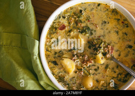 A large bowl of Zuppa Toscana soup shown with bright green napkin and spoon. Tuscan stew, Italian cuisine. Stock Photo