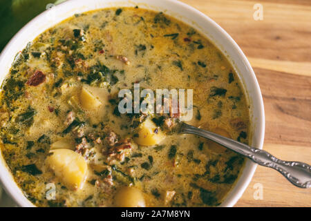 A large bowl of Zuppa Toscana soup shown with bright green napkin and spoon. Tuscan stew, Italian cuisine. Stock Photo