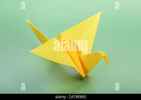 Origami bird on green background. Japanese folded paper swan. Peace and hope symbol Stock Photo