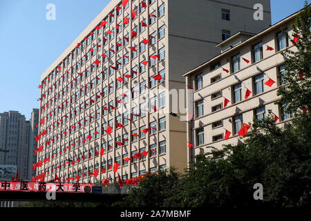 Chinese national flags flutter on the windows at the campus of Liaoning University Of Traditional Chinese Medicine to mark the upcoming National Day i Stock Photo