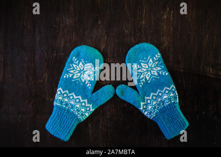 a pair of blue knitted mittens on a dark blue-green-brown wooden Stock Photo