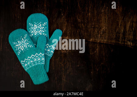 a pair of blue knitted mittens on a dark blue-green-brown wooden Stock Photo