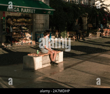 Guy enjoying the sun on the bench at the seaside at Herceg Novi, Montenegro. Stock Photo