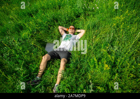 Man lying down on grass with laptop. Top view Stock Photo