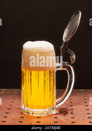 A cold, crisp mug of beer in a traditional bavarian pint glass with a foamy head Stock Photo