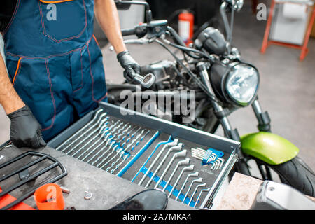 Mechanic getting wrenches from the metal tool box, repairing motorcycle in the workshop, close-up Stock Photo