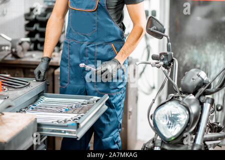 Mechanic getting wrenches from the metal tool box, repairing motorcycle in the workshop, close-up Stock Photo