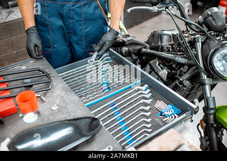 Mechanic getting wrenches from the metal tool box, repairing motorcycle in the workshop, close-up Stock Photo