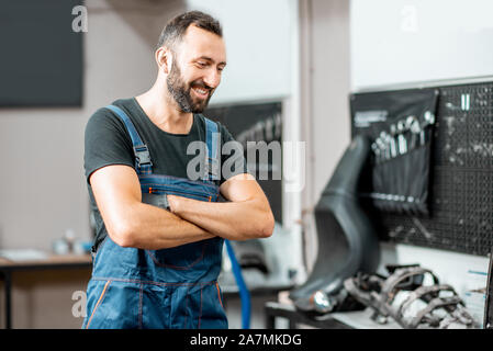 Portrait of a handsome cheerful service worker in working overalls in the workshop for motorcycles repairment Stock Photo