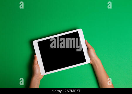 Kid hands holding white tablet computer on green background Stock Photo