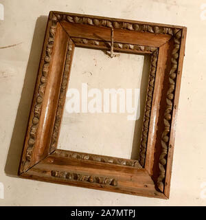 Old wooden empty photo frame hanging on the wall nailed rusty steel nail. Vintage photo frame made of natural oak tree for fashion collage. Blank styl Stock Photo