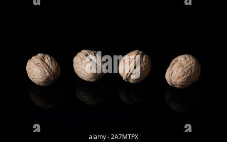 Walnuts in their shells on black reflective surface Stock Photo
