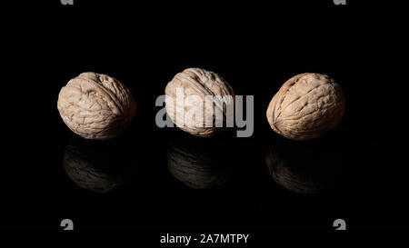Walnuts in their shells on black reflective surface Stock Photo