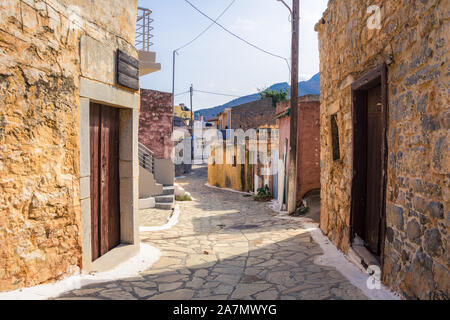 Narrow street with colorful stone houses in the old village of Pano Elounda, Crete, Greece.