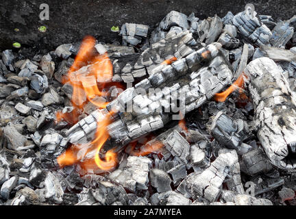 Beautiful red flame from slice wood, dark grey black coals inside metal brazier. Wood burning in the brazier on bright yellow flame. Flames fire prepa Stock Photo
