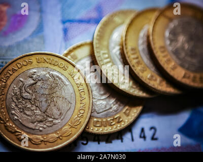 Closeup of Mexican coins (10 pesos) with  a bank note as a background. Selective focus Stock Photo