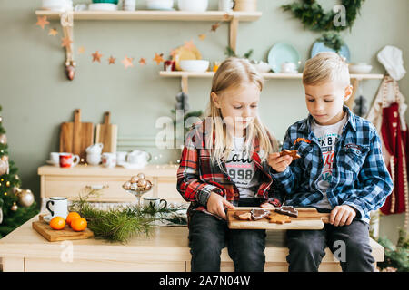 Portrait of a little brother and sister waiting for Santa in the kitchen Stock Photo