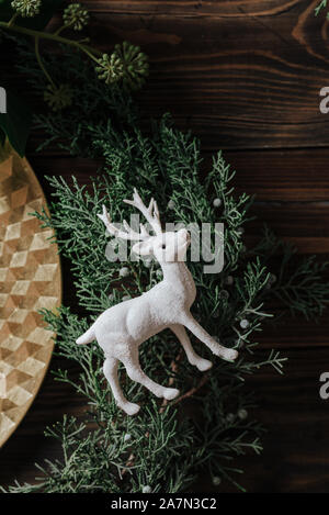 Christmas table set, reindeer figurine detail on natural pine branches, Wooden background Stock Photo